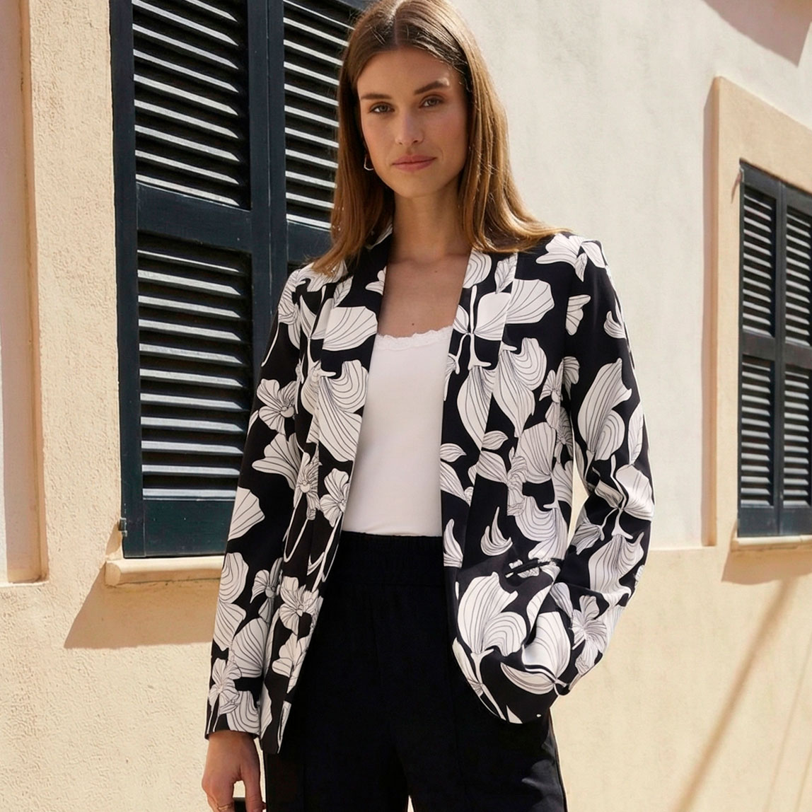 Schwarz-weißer Blumenblazer über weißen Top und schwarzer Hose.