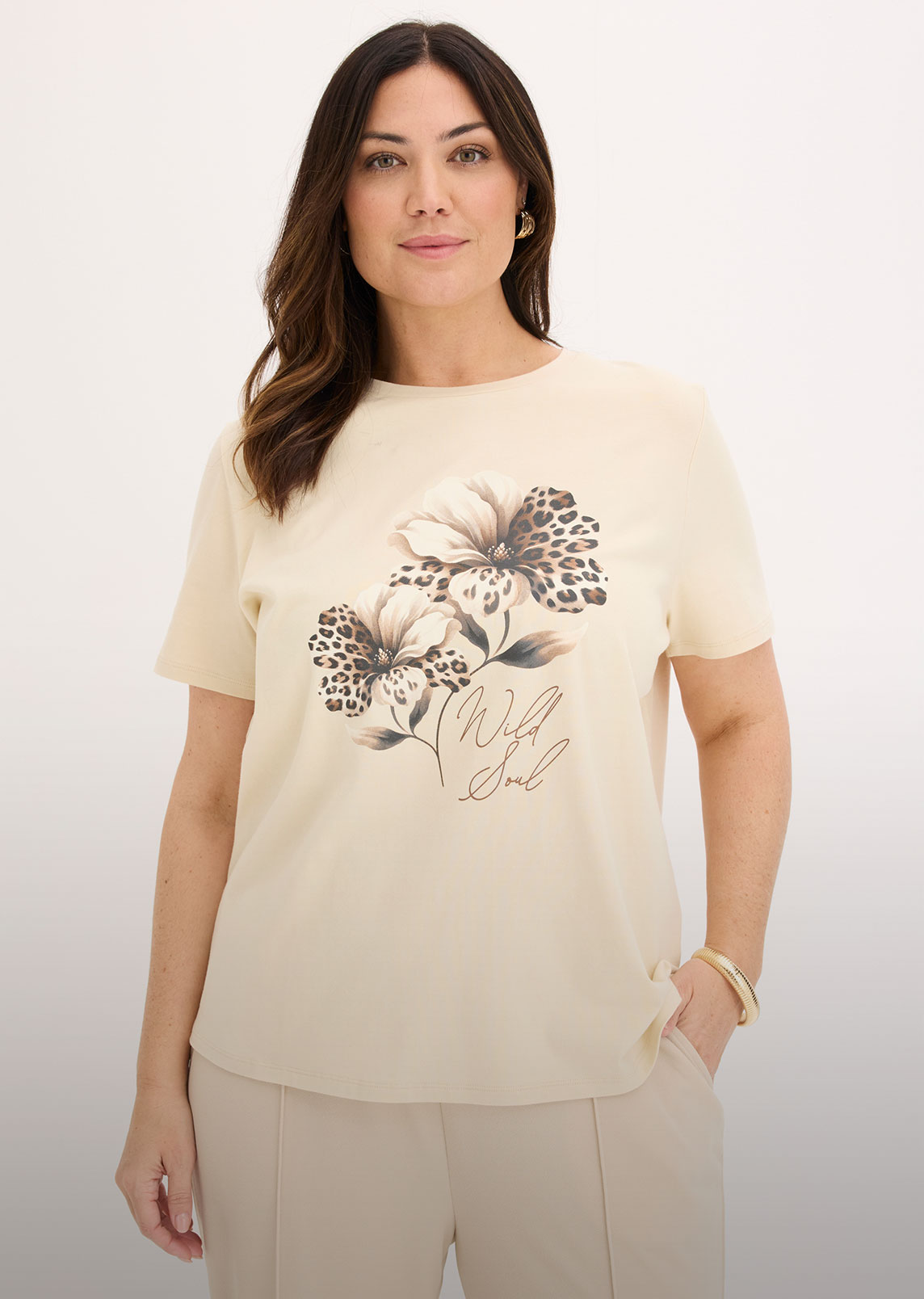 Beiges T-Shirt mit Blumendesign, Leopardenmuster und "Wild Soul" Schriftzug, dazu helle Hose.