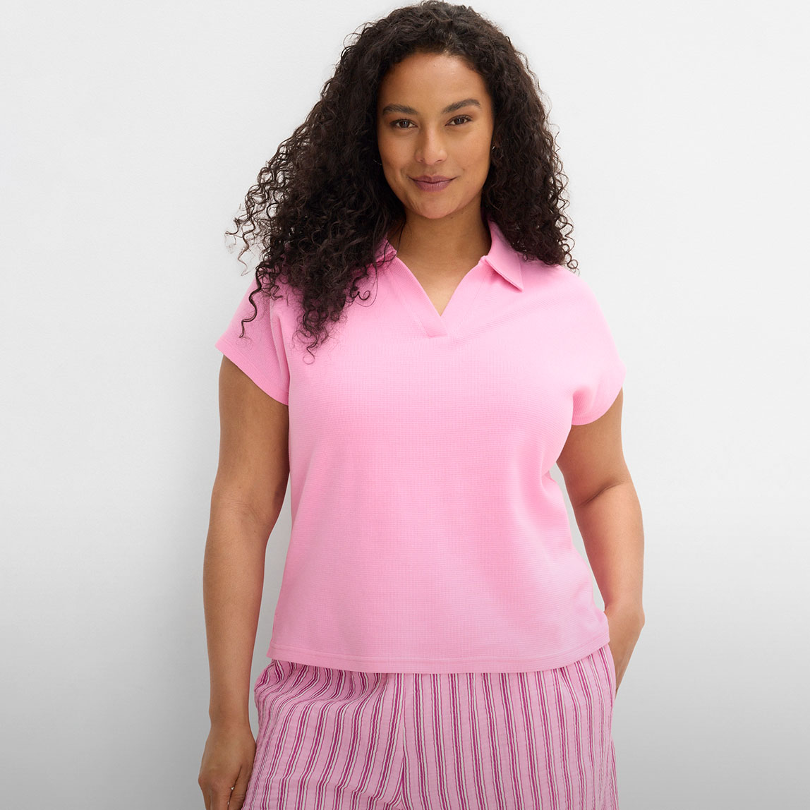 Kurzärmeliges, rosa Poloshirt und eine gestreifte Hose.