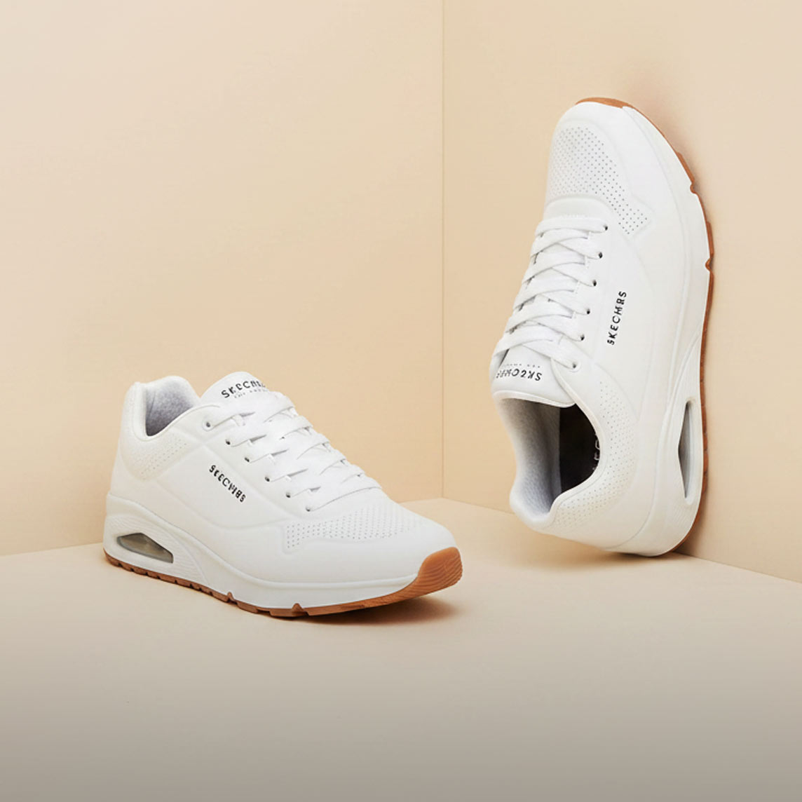 Zwei weiße Skechers-Sneaker mit brauner Sohle, sportlich und bequem.