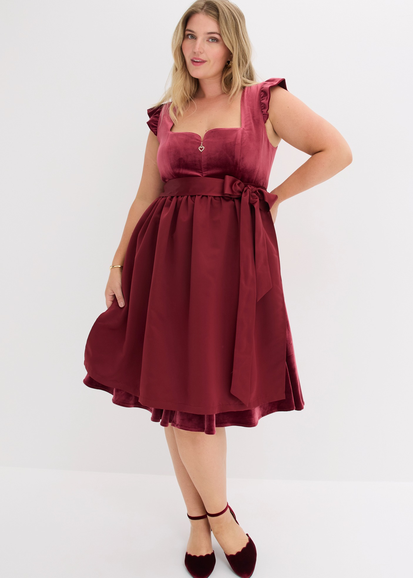 Samtiges, bordeauxrotes Kleid mit Schleife und Rüschenärmeln, dazu passende Flats.