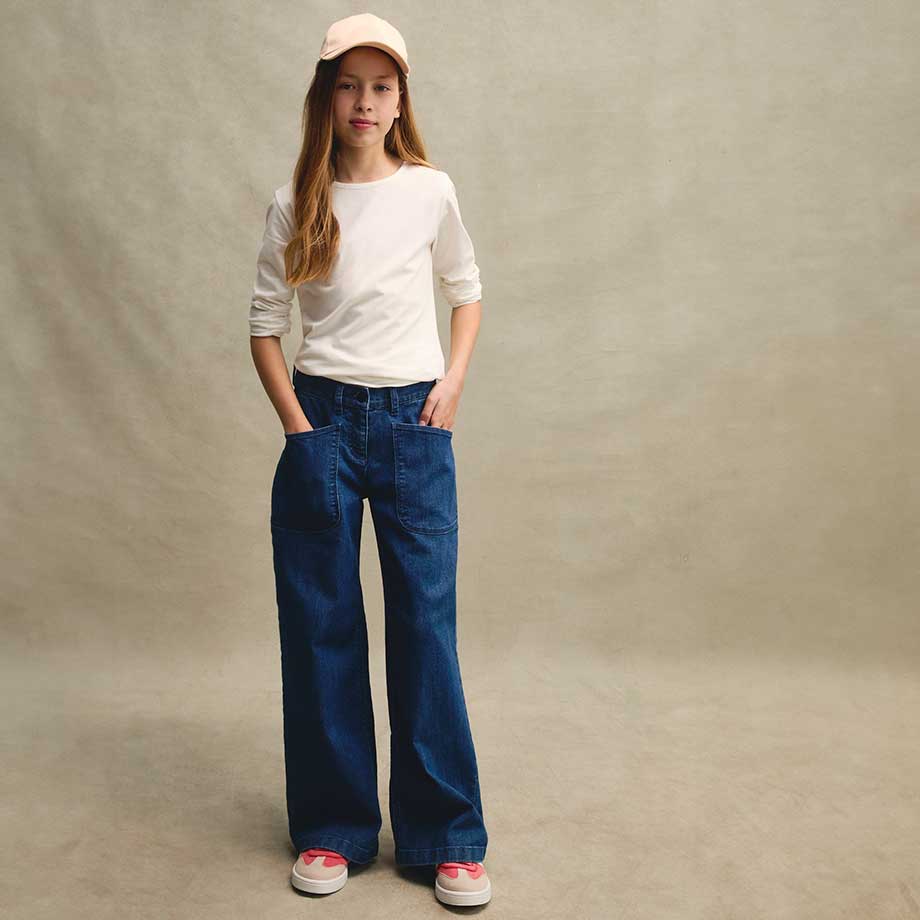 Weißes Spitzentop, weite Jeans und Baseballkappe - lässiger Retro-Look mit modernem Twist.