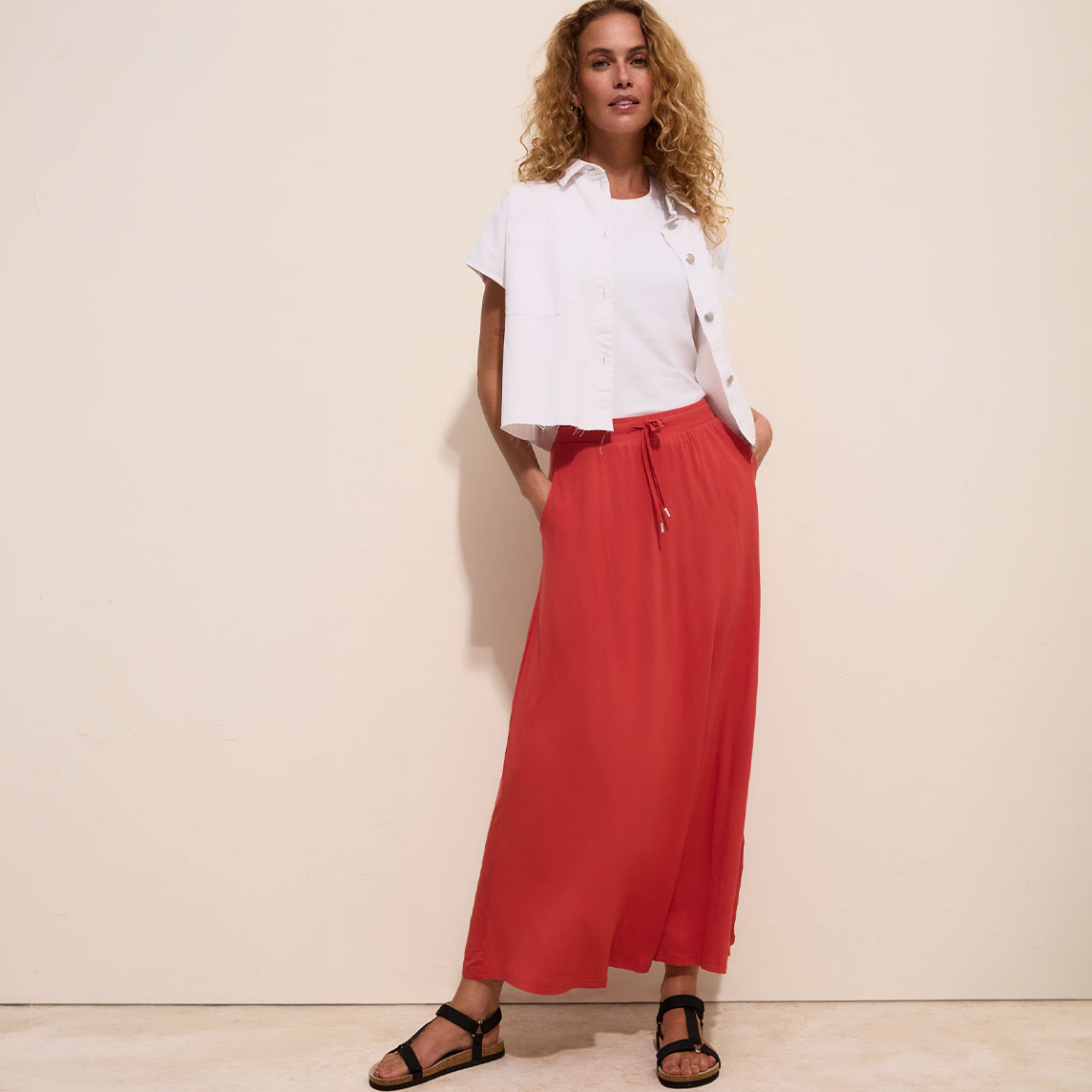Lässige weiße Bluse, weißes Shirt, langer roter Rock und schwarze Sandalen.