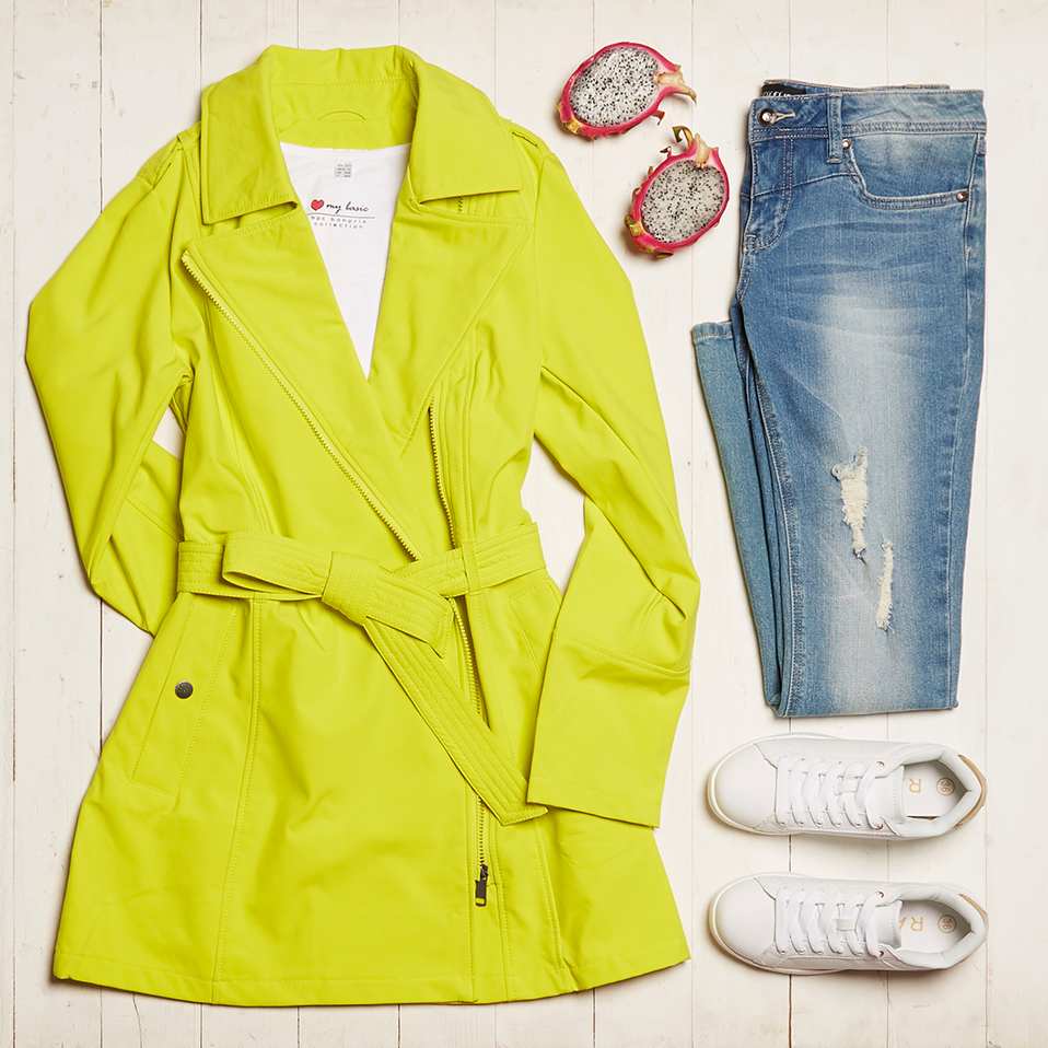 Leuchtend gelber Mantel, zerrissene Jeans und weiße Sneakers: ein stylischer Frühlingslook mit Farbtupfer.