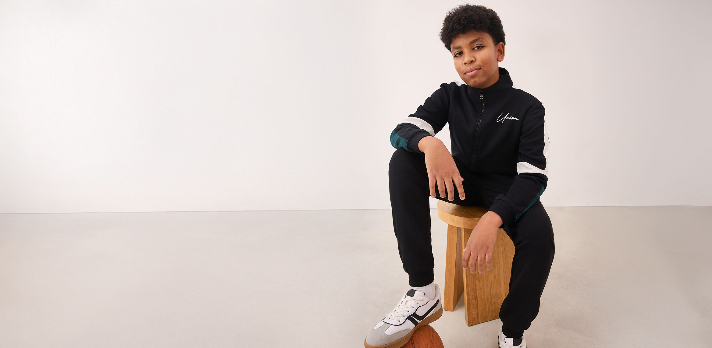 Sportliches Outfit mit schwarzem Trainingsanzug und weißen Akzenten. 