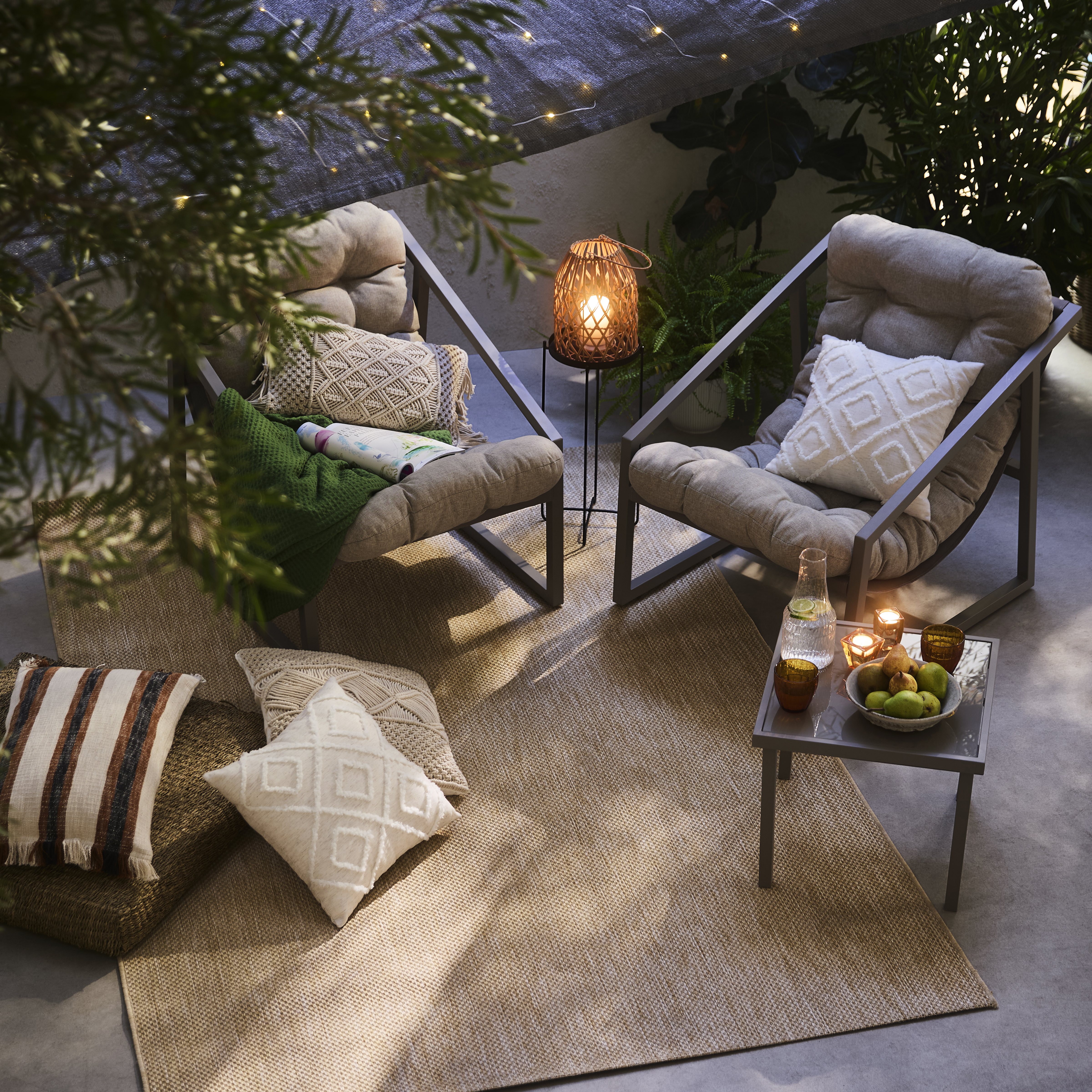 Gemütliche Outdoor-Lounge mit hellen Kissen und weichen Textilien.