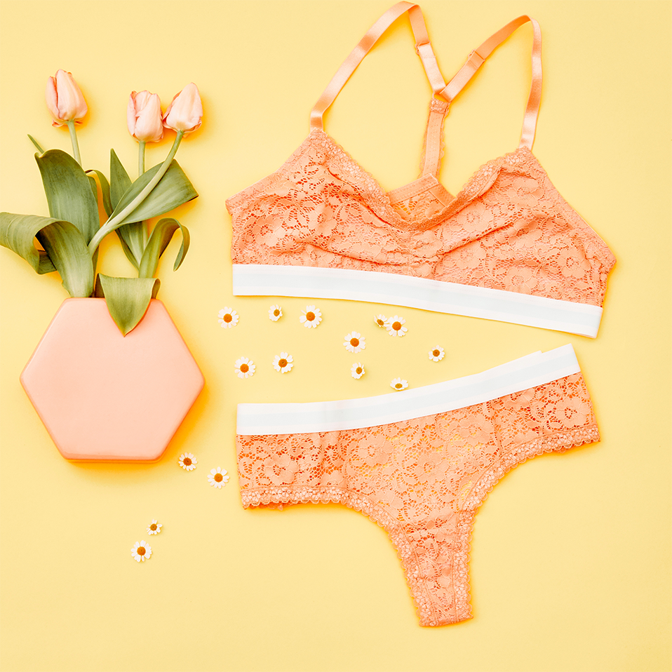 Zartes Spitzen-Lingerie-Set in Apricot: Verführerischer BH und passender Slip auf gelbem Hintergrund.