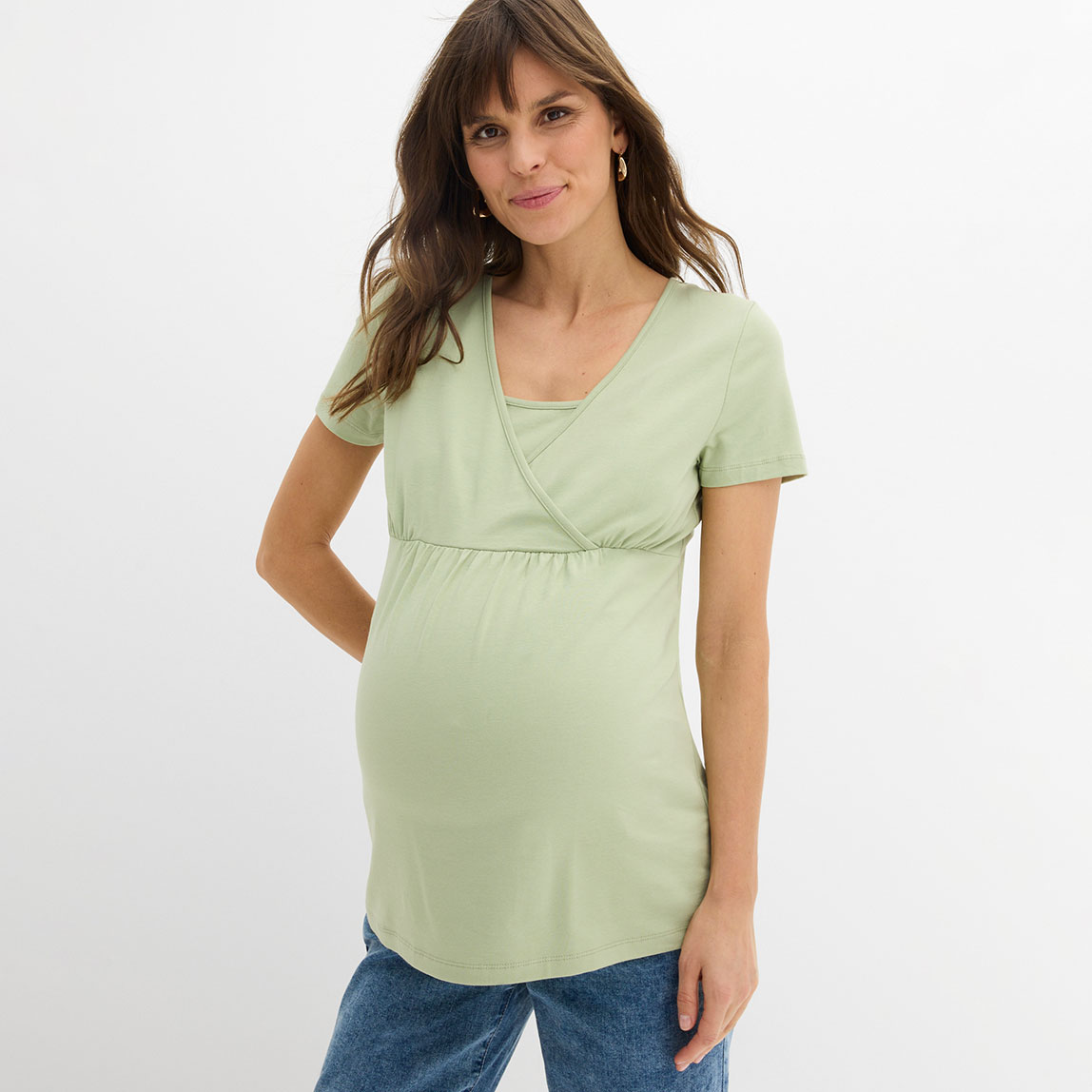 Mintgrünes Umstandsshirt mit kurzen Ärmeln und blaue Jeans.