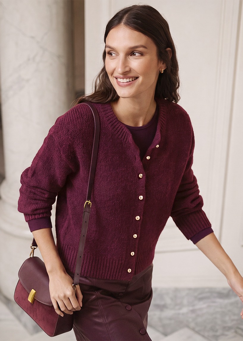 Bordeauxroter Cardigan mit Perlmuttknöpfen, dazu passender Rock und Tasche.
