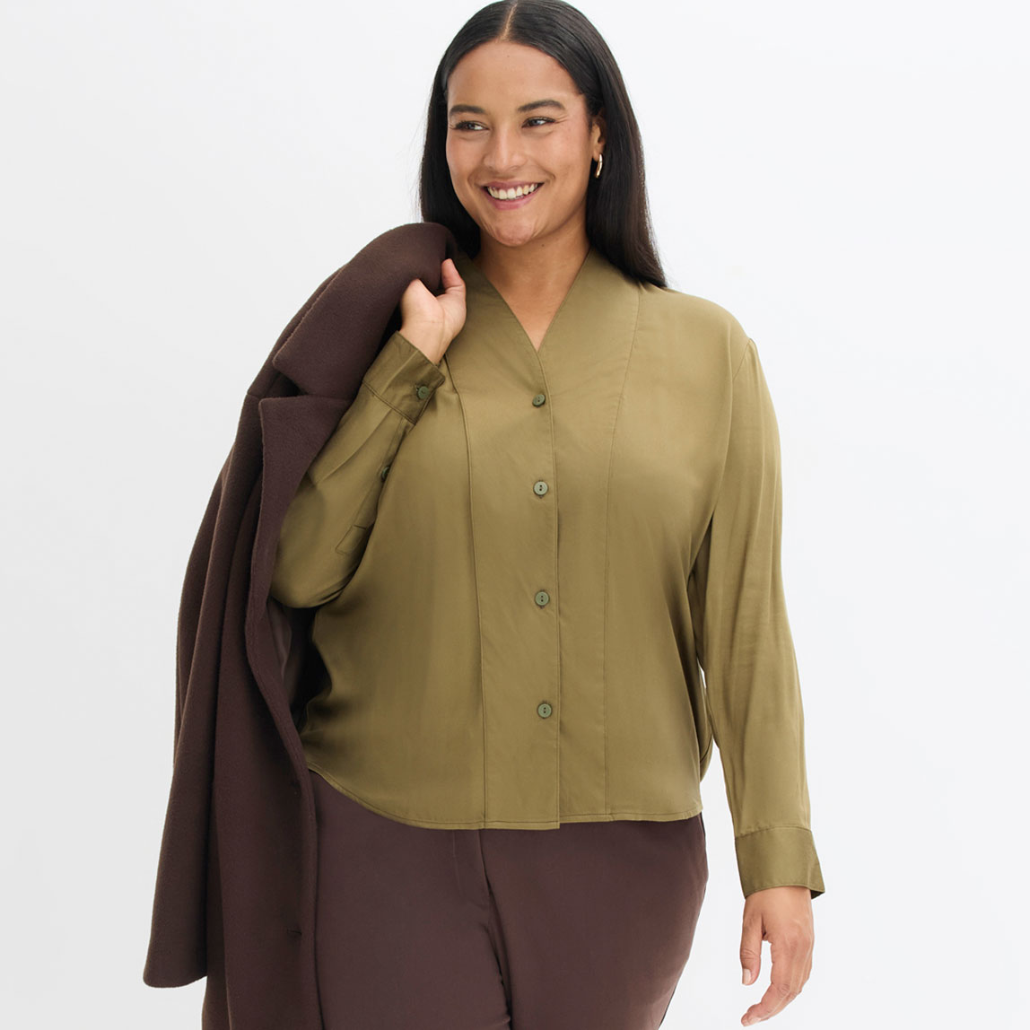 Kombination aus olivgrüner Bluse und braunem Mantel. 