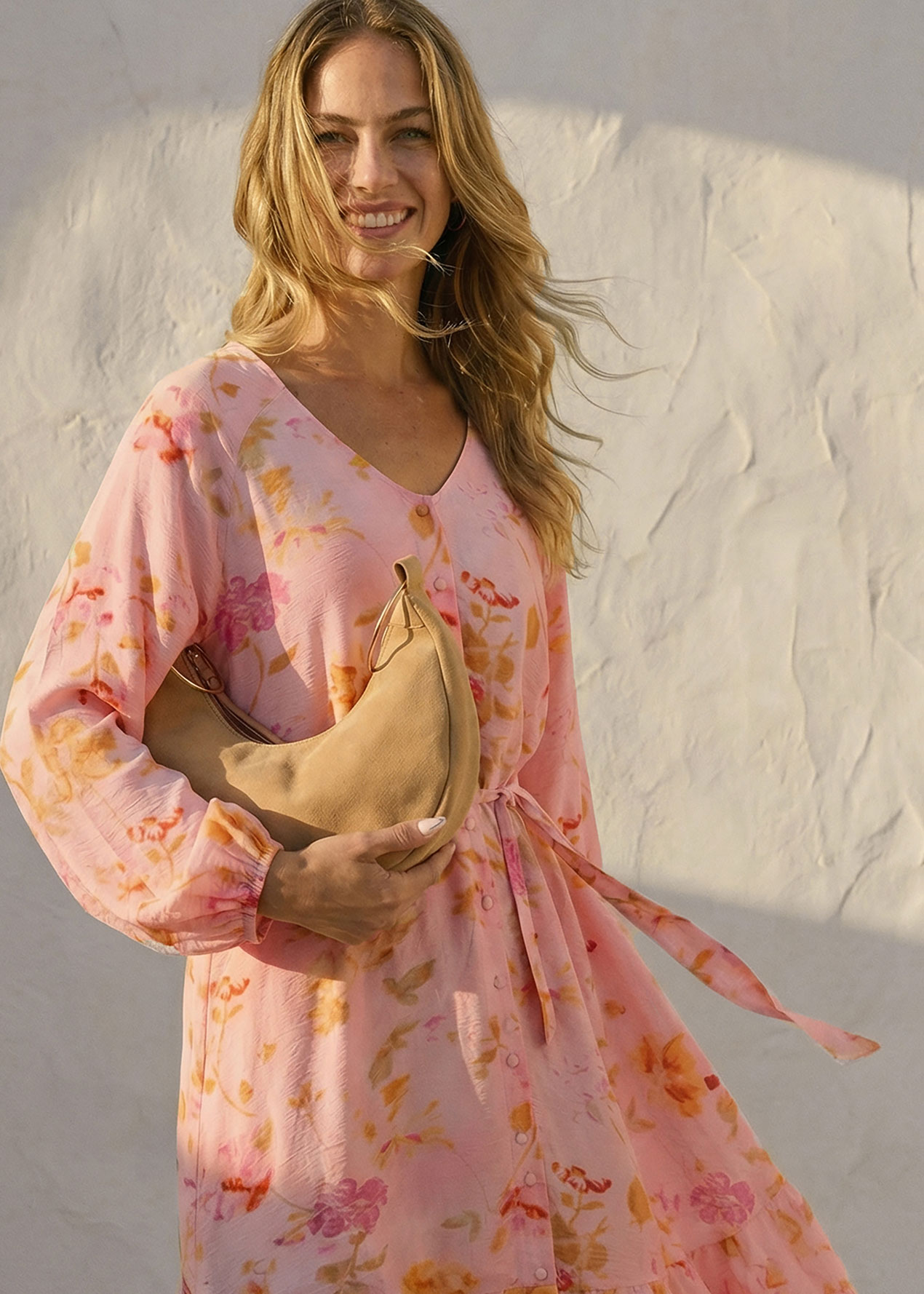 Frau trägt luftiges geblümtes rosa Sommerkleid mit langen Ärmeln.