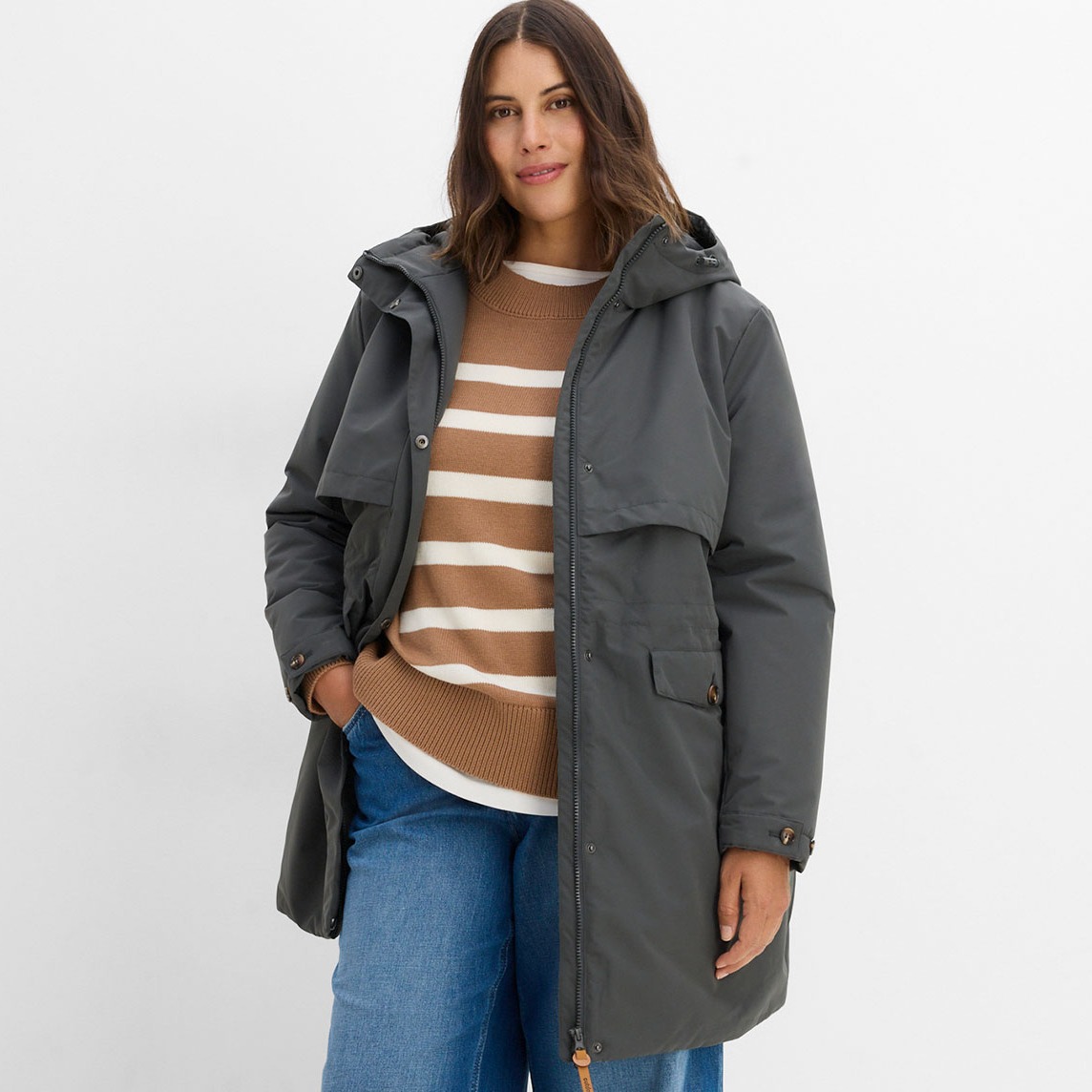 Graue Funktions-Jacke, gestreifter Pullover und bequeme Jeans.
