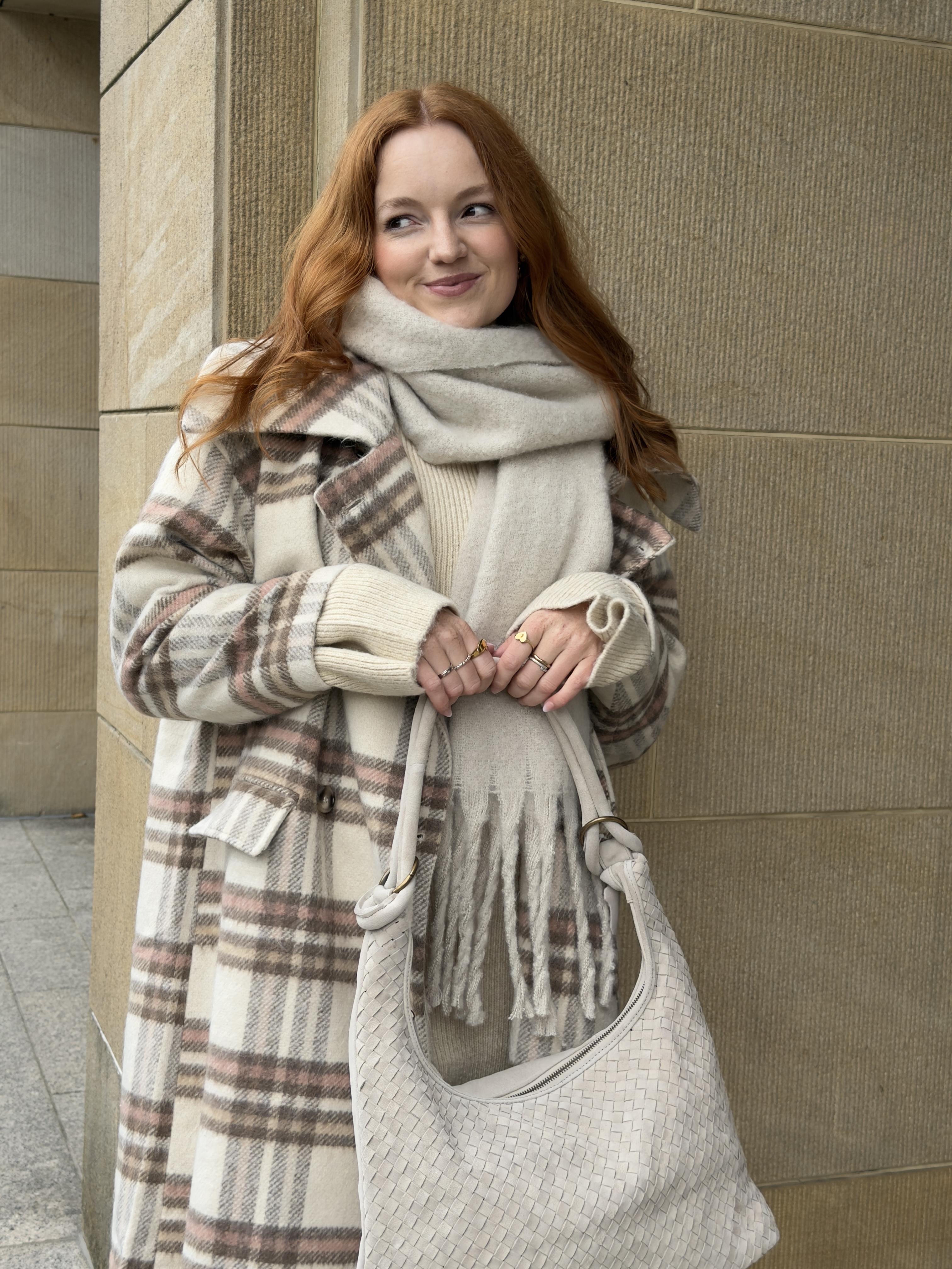 Karierter Wintermantel, weißer Schal und Handschuhe. Gestrickte Tasche.