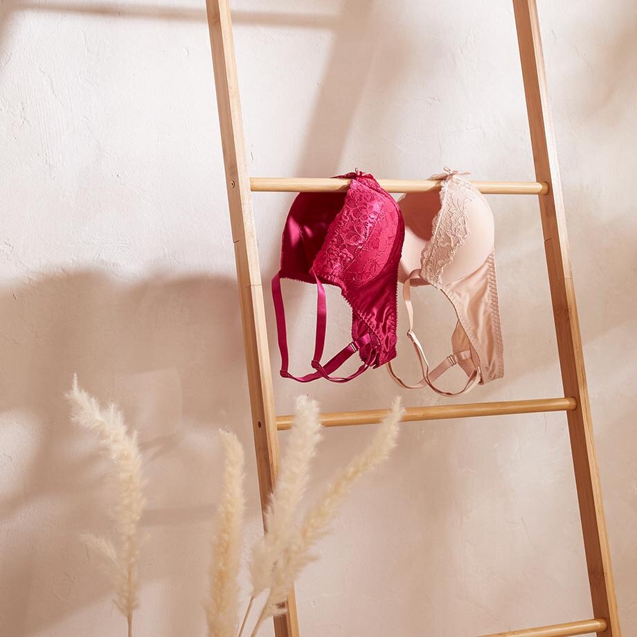 Zarte Dessous in Rosa und Pink hängen an einer Holzleiter, elegant präsentiert.