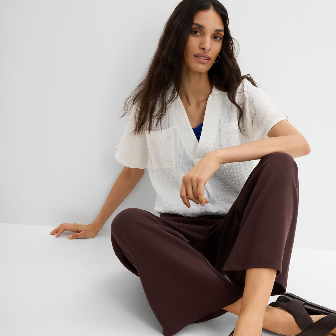 Lässige weiße Bluse, weite braune Hose und bequeme, dunkle Schuhe.