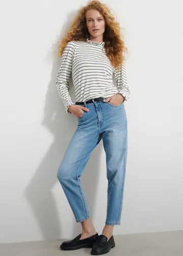 Gestreiftes Langarmshirt, helle Jeans, schwarzer Gürtel und bequeme Loafer.