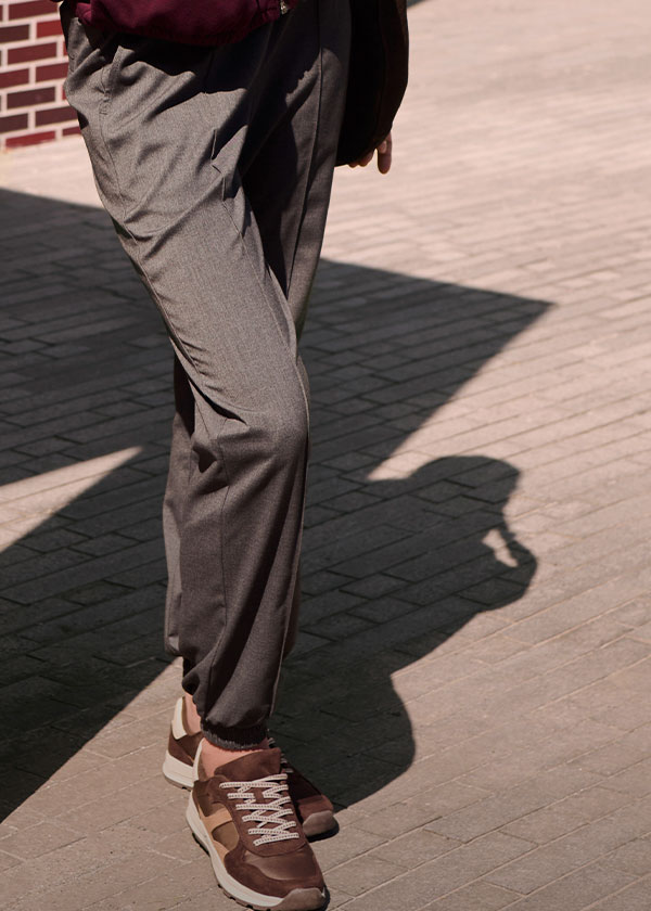 Graue Stoffhose und braune Sneaker definieren den lässig-eleganten Look.