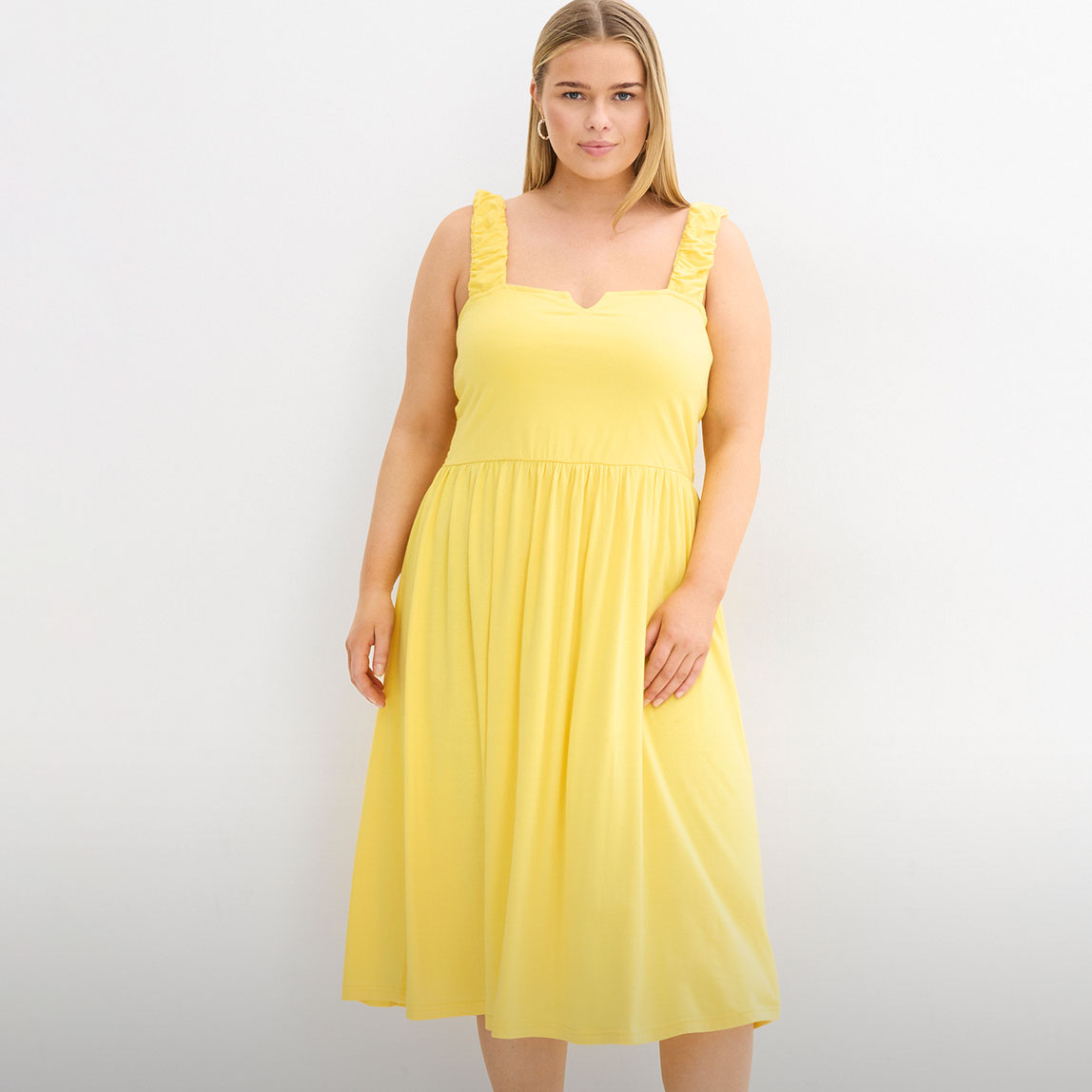 Gelbes Midikleid mit gerafftem Oberteil, fließendem Rock und Rüschenträgern.
