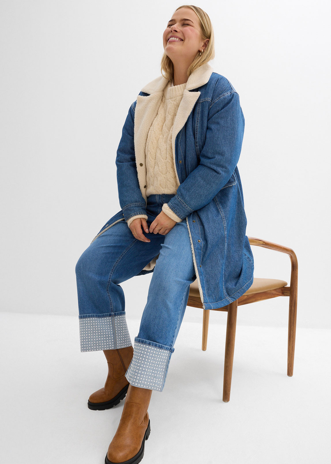 Jeanslook mit langem Mantel, beigem Pullover und Jeans.