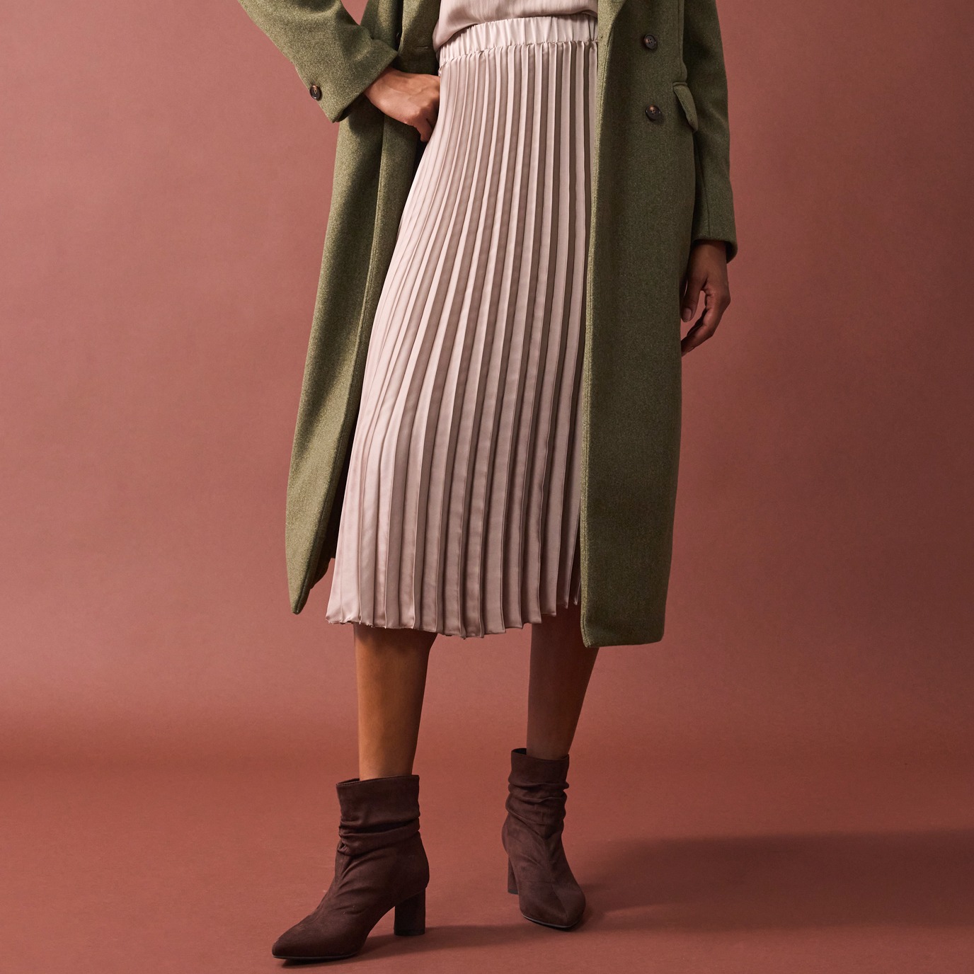 Langer grüner Mantel trifft auf plissiertes rosa Rock.