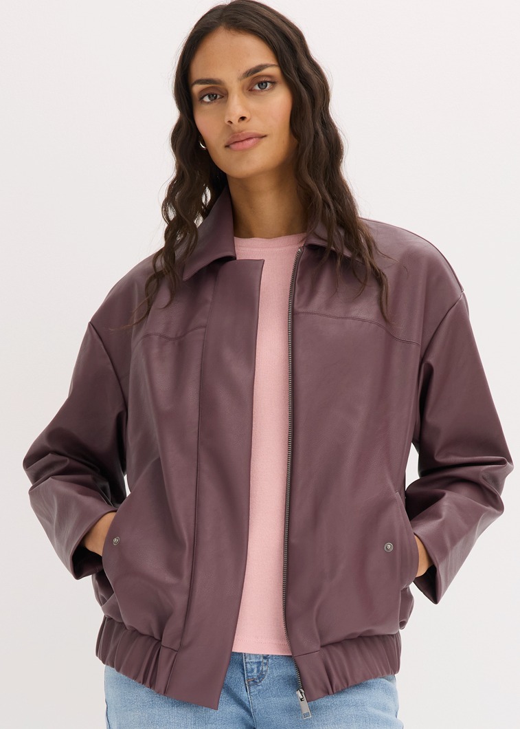 Modische pflaumenfarbene Kunstlederjacke kombiniert mit rosa T-Shirt und blauen Jeans.