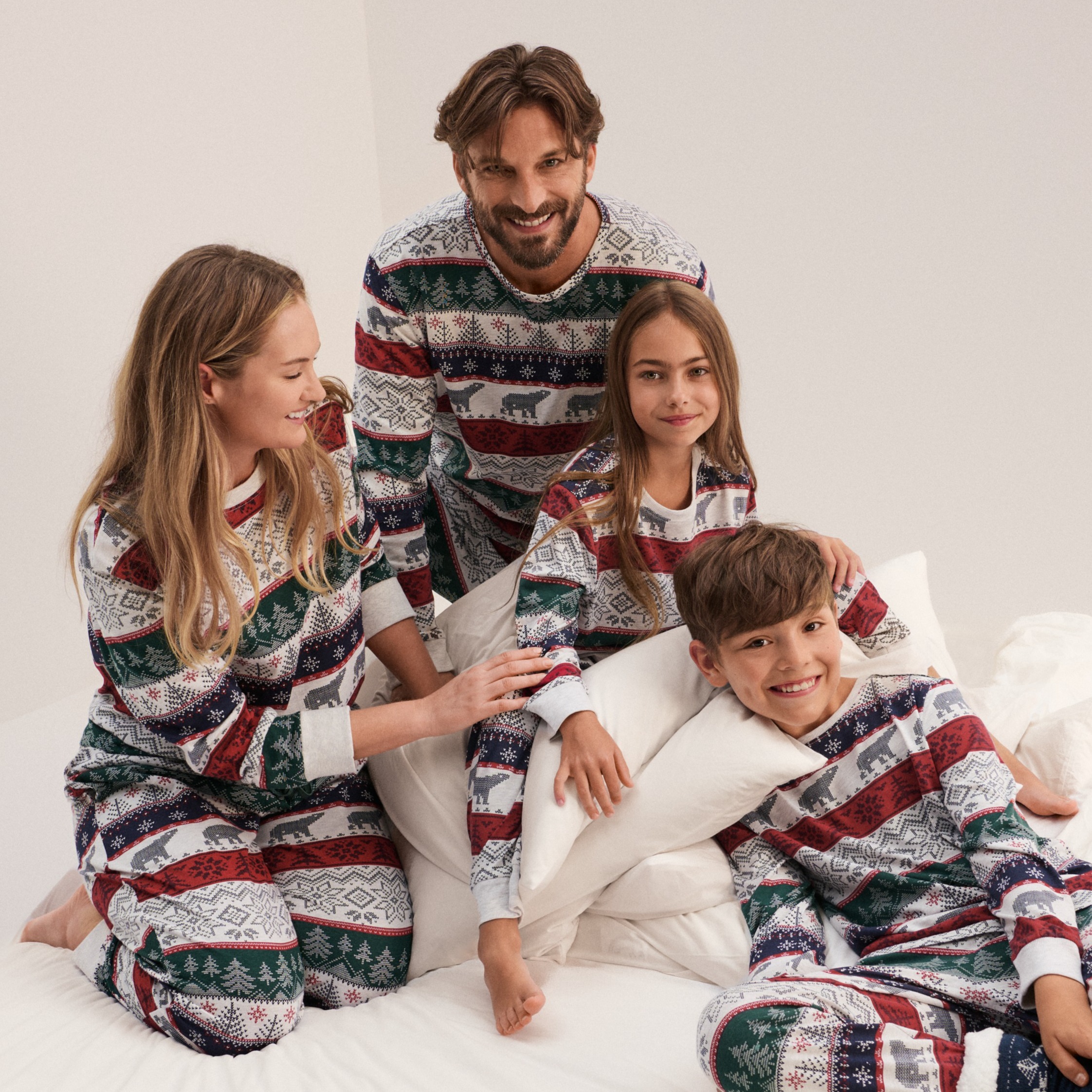 Gemütliche Winterstimmung mit passenden Pyjamas: Weiß-rot-blaue Muster zieren die kuscheligen Schlafanzüge der Familie.